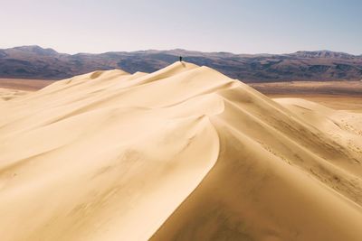 Tourist on sand dune in desert against sky