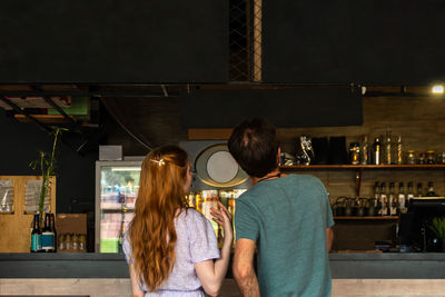 Young couple choosing dishes at bar from menu