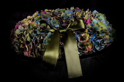 Close-up of artificial flowers with ribbon against black background