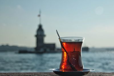 Close-up of drink on table at sea against sky