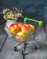 Basket with nectarines and a bouquet of daisies in a small light vase 