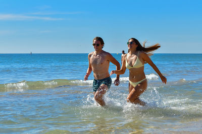 Full length of friends on beach against sky