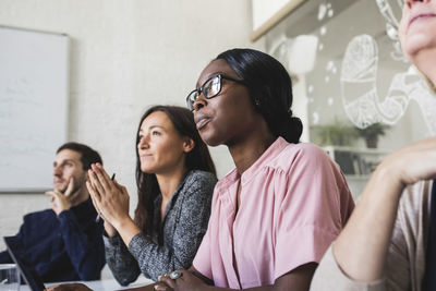 Creative business people listening while sitting in board room during meeting