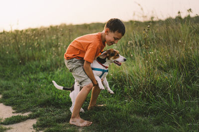 Portrait of a little boy playing with his jack russell dog in the park.