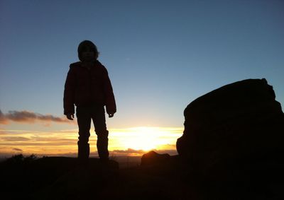 Silhouette of people standing on landscape at sunset