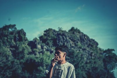 Young man looking at mountain against sky