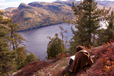 Rear view of woman sitting by lake