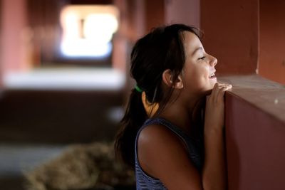 Side view of happy girl looking over retaining wall in stable