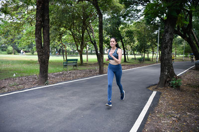 Full length of young woman running on road in park