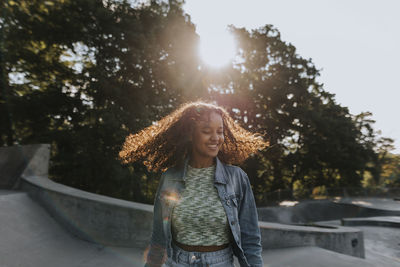 Smiling teenage girl looking at skate park looking away