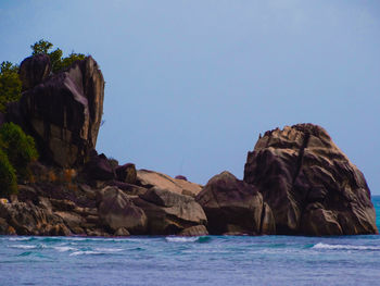 Rock formation in sea against clear blue sky
