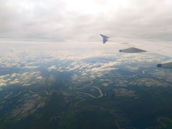 Aerial view of airplane wing over landscape against sky