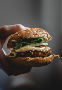 Close-up of hand holding burger against white background