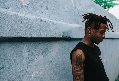 Side view of young man looking away against wall