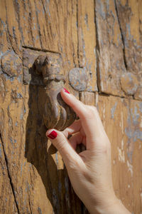 Cropped hand of woman holding door knocker