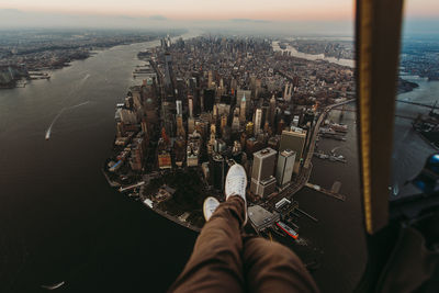 Low section of man sitting in helicopter over buildings in city