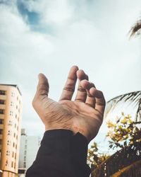 Low angle view of human hand against sky