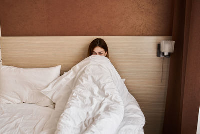 Portrait of woman resting on bed at home