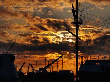 Silhouette of sailboat against dramatic sky during sunset