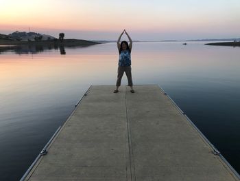 Full length of woman standing on shore against sky during sunset