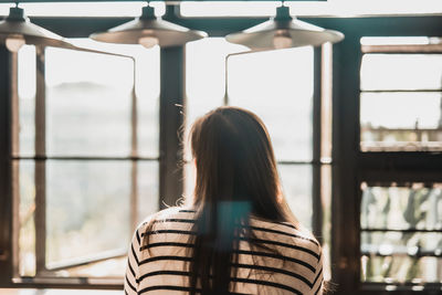 Rear view of woman looking through window