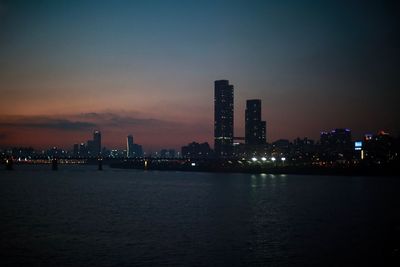 Illuminated buildings in city against sky at night