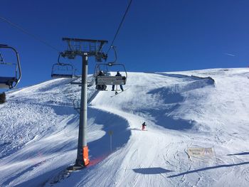 Ski lift over snowcapped mountains against clear sky