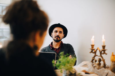 Business people discussing while sitting at table against wall in creative office