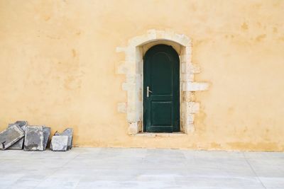 Closed green door of old light yellow colored building