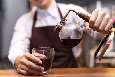 Midsection of barista making coffee at cafe