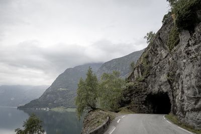 Road amidst trees and mountains against sky