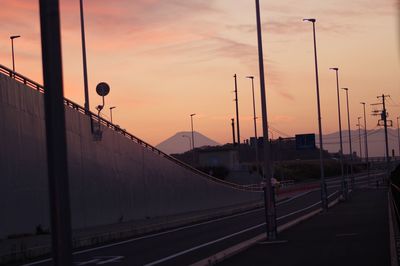 Street at railroad station against sky during sunset