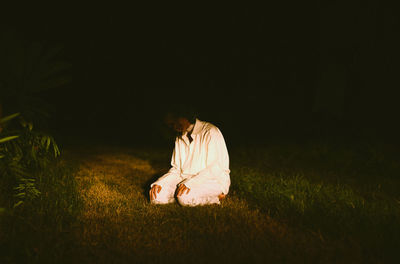 Woman sitting on field at night