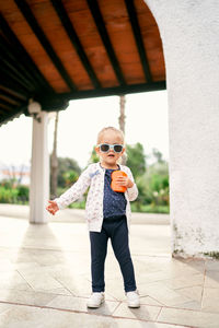 Young woman wearing sunglasses while standing against wall