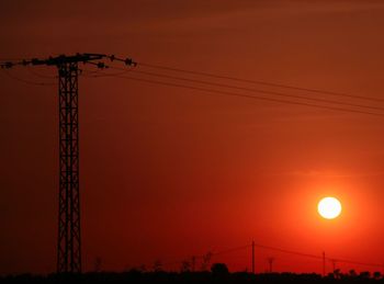 Low angle view of silhouette electricity pylon against romantic sky