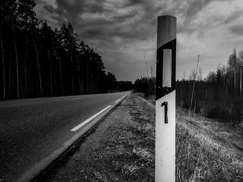 Road amidst trees on field against sky