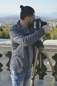 Man standing by railing against sky