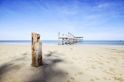 Wooden posts on beach against sky