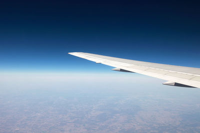 Aerial view of aircraft wing against clear blue sky