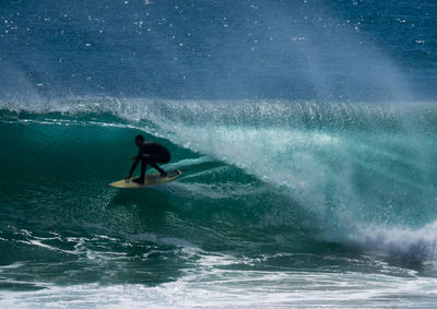 Full length of man surfing on wave at sea