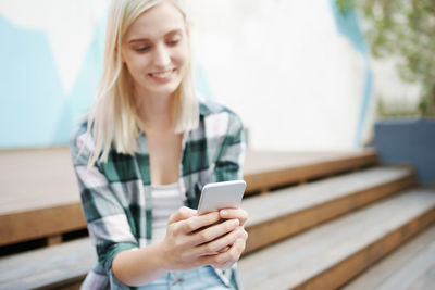 Smiling young woman using mobile phone