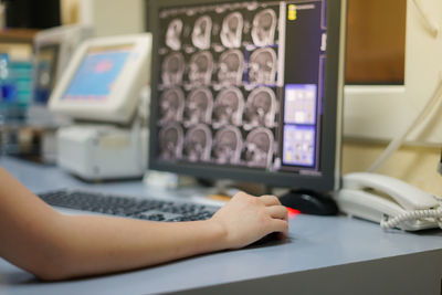 Cropped hand of doctor using computer at table in hospital