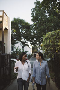 Female designers discussing while walking on footpath