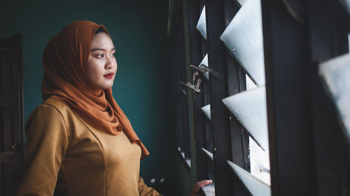 Woman looking through window at home