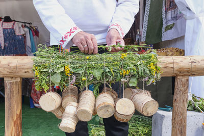 Hands of senior man weaving rug from field plants, floral carpet, on manual wooden loom. handmade