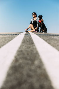 Woman sitting on street against sky