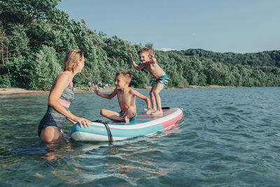 People enjoying in water against trees