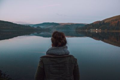 Rear view of woman standing by lake