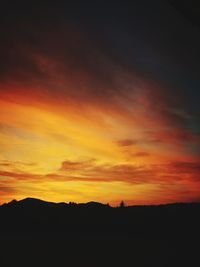 Silhouette landscape against dramatic sky during sunset