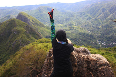 Rear view of man standing on mountain against sky